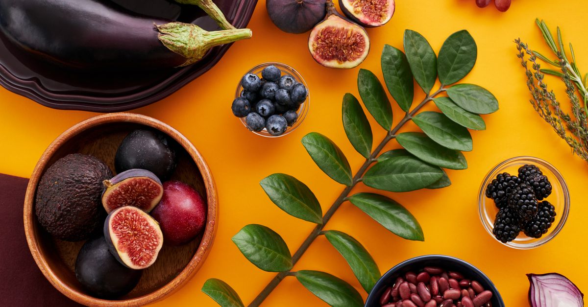 Top view of colorful fruits and vegetables on a vibrant orange background, perfect for healthy lifestyle concepts.